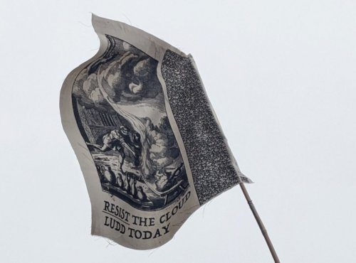 Flag against grey sky: "Resist the cloud, ludd today"