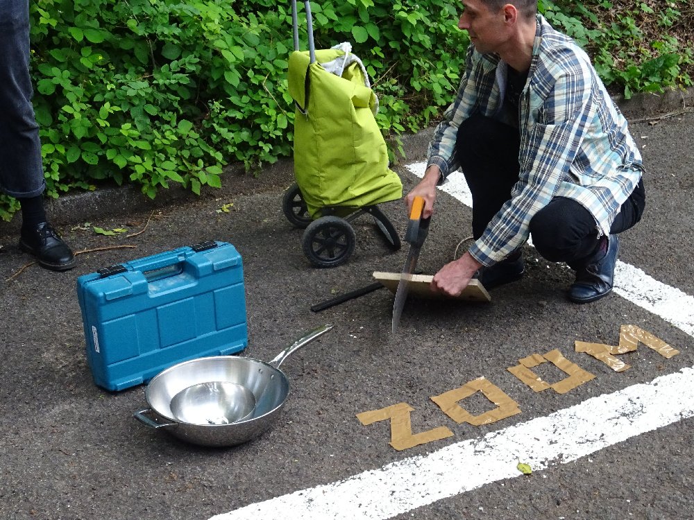 "A person using a saw while sitting on a parking lot marked ZOOM"