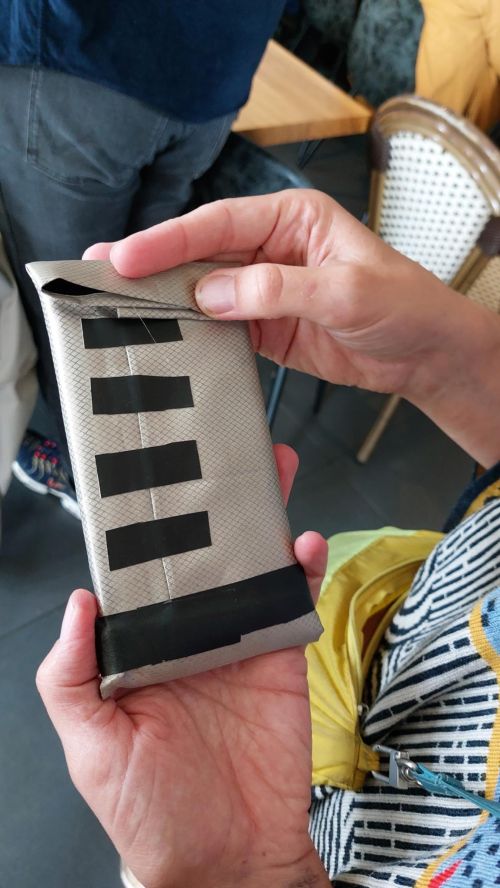 Picture of people placing their phone in the Infraday Pockets. Example of Infraday package: a phone contained in Faraday material.