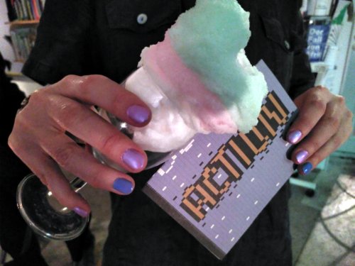 Person with glittery purple nailpolish holds a glass filled with clouds made of cotton wool. They hold a card, that reads "action"