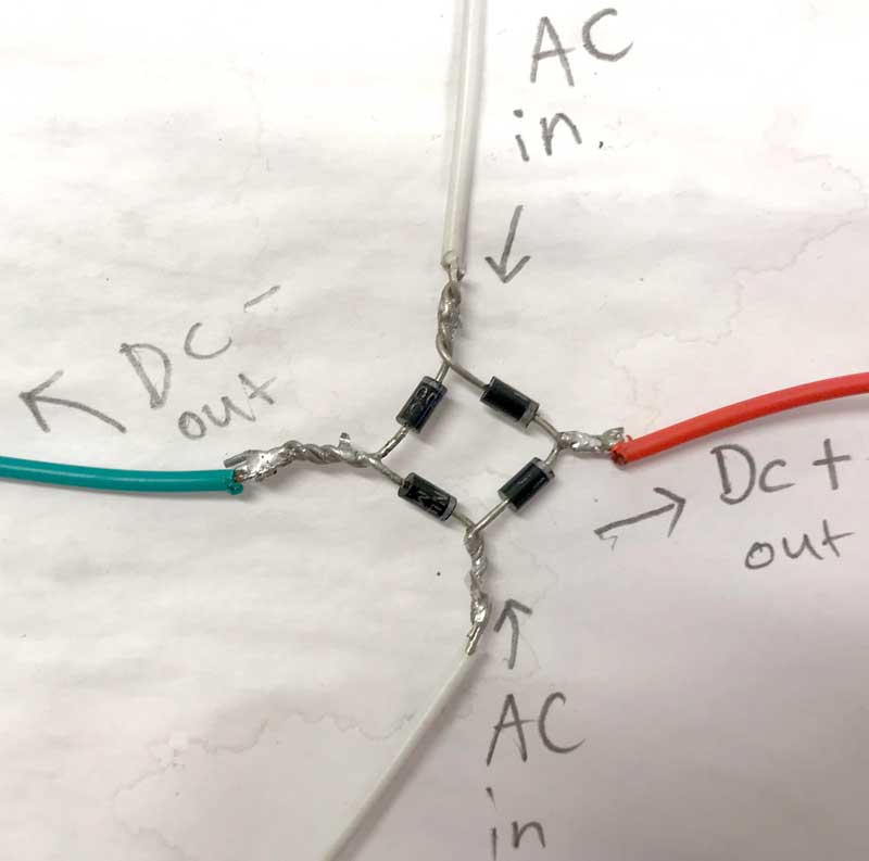 four silicon diode are connected in a diamond shape, with soldered cables on each corner. The diodes have a line on them to indicate the flow of electric charge; where two diode lines meet, the DC positive wire is soldered. Where two diode lines face away from each other, the negative DC wire is soldered. The other two corners are the AC inputs.