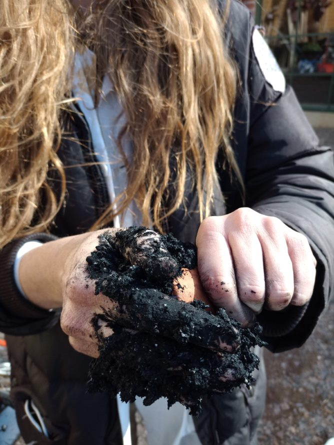 hands covered in gooey black matter, which is seitan mixed with charcoal